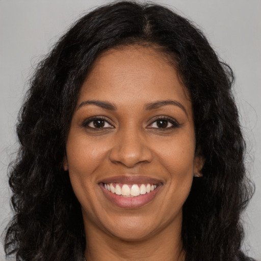 Joyful black young-adult female with long  brown hair and brown eyes