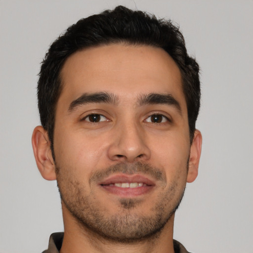 Joyful latino young-adult male with short  brown hair and brown eyes