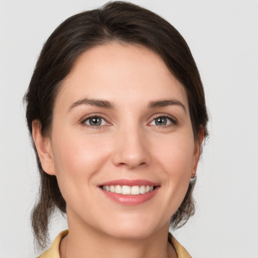 Joyful white young-adult female with medium  brown hair and grey eyes