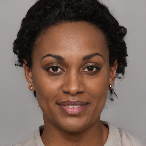 Joyful black young-adult female with short  black hair and brown eyes