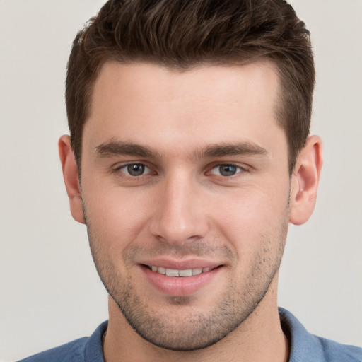 Joyful white young-adult male with short  brown hair and grey eyes