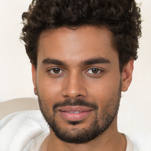 Joyful black young-adult male with short  brown hair and brown eyes