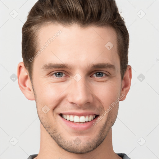 Joyful white young-adult male with short  brown hair and grey eyes