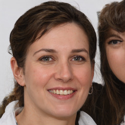 Joyful white young-adult female with medium  brown hair and blue eyes