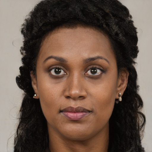 Joyful black young-adult female with long  brown hair and brown eyes