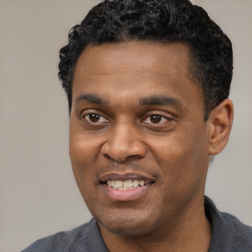 Joyful black young-adult male with short  black hair and brown eyes