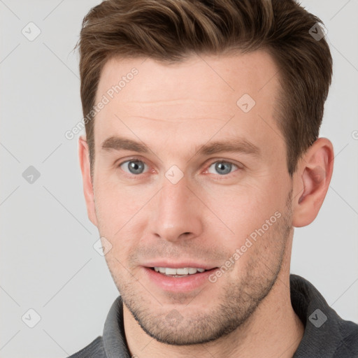 Joyful white young-adult male with short  brown hair and grey eyes