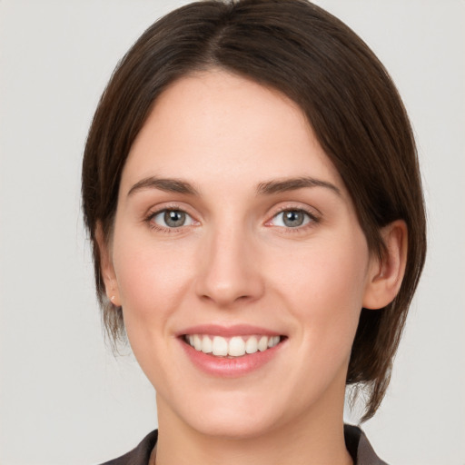 Joyful white young-adult female with medium  brown hair and grey eyes