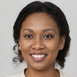 Joyful black adult female with medium  brown hair and brown eyes