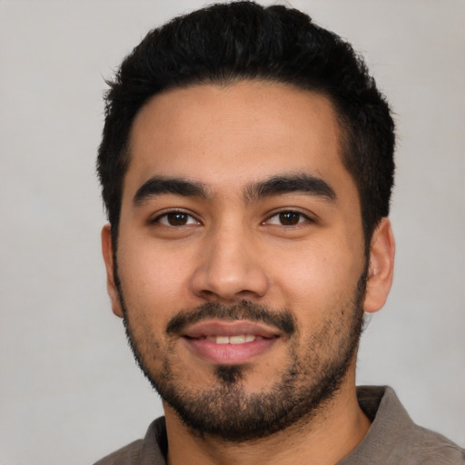 Joyful latino young-adult male with short  black hair and brown eyes