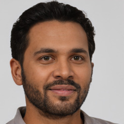 Joyful latino young-adult male with short  black hair and brown eyes