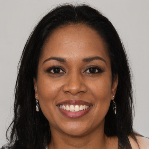 Joyful black young-adult female with long  brown hair and brown eyes