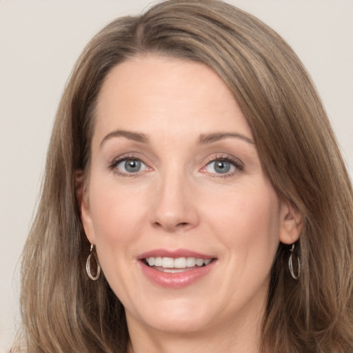 Joyful white adult female with long  brown hair and grey eyes