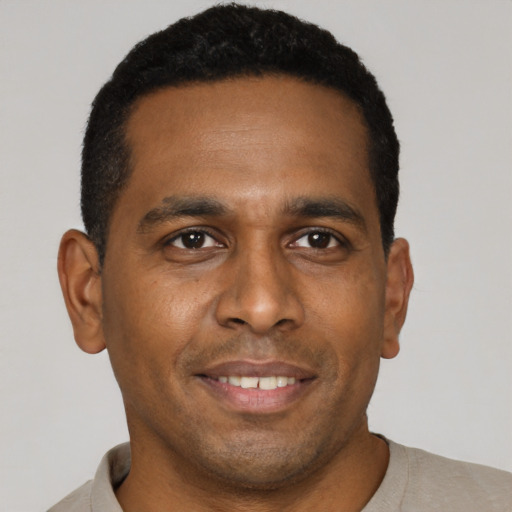 Joyful black young-adult male with short  brown hair and brown eyes