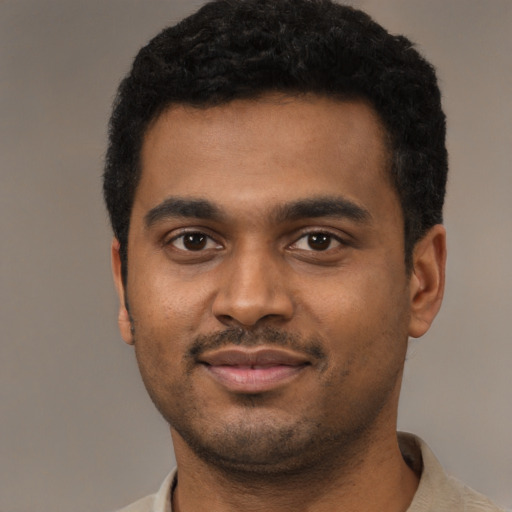 Joyful black young-adult male with short  black hair and brown eyes