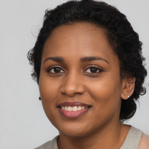 Joyful black young-adult female with long  black hair and brown eyes