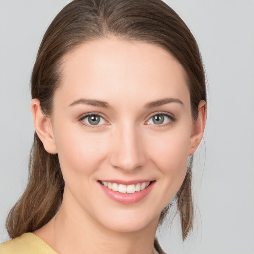 Joyful white young-adult female with medium  brown hair and grey eyes