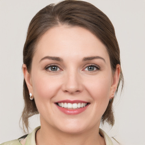 Joyful white young-adult female with medium  brown hair and grey eyes