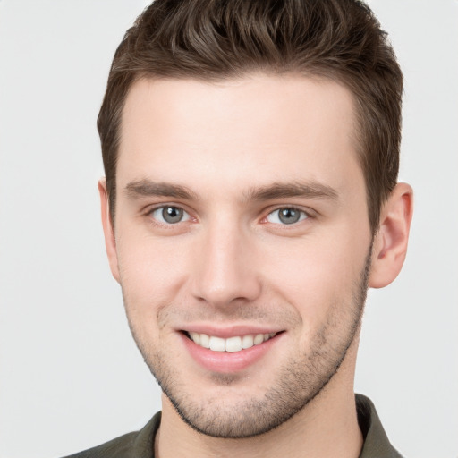 Joyful white young-adult male with short  brown hair and grey eyes