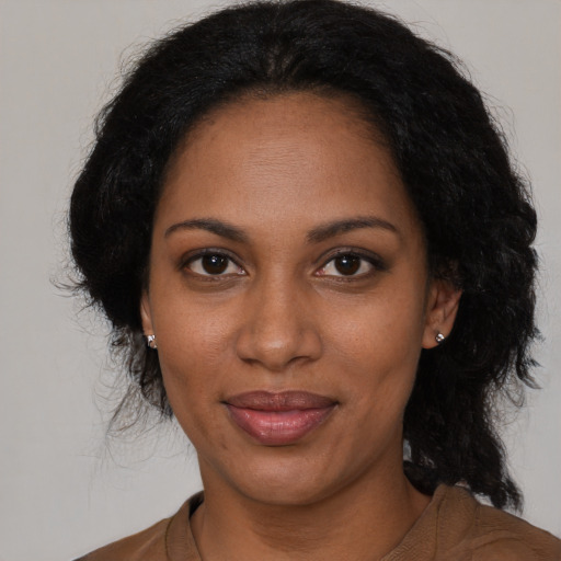 Joyful black adult female with long  brown hair and brown eyes