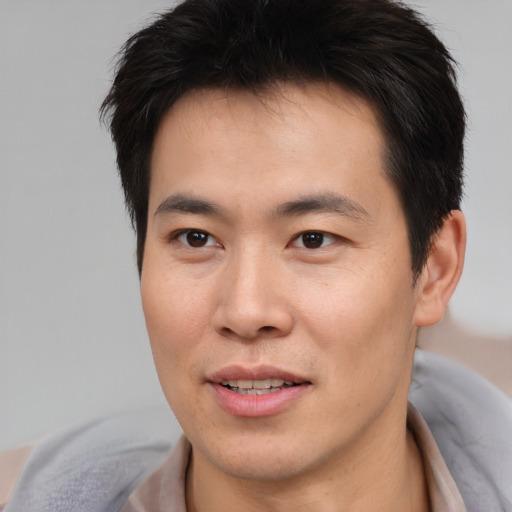 Joyful asian young-adult male with short  brown hair and brown eyes