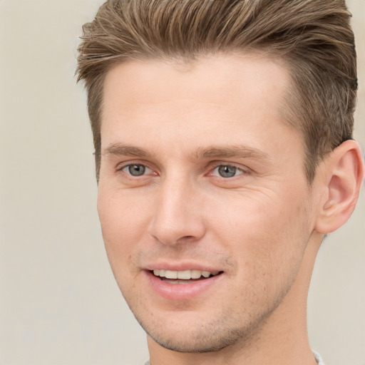 Joyful white young-adult male with short  brown hair and grey eyes