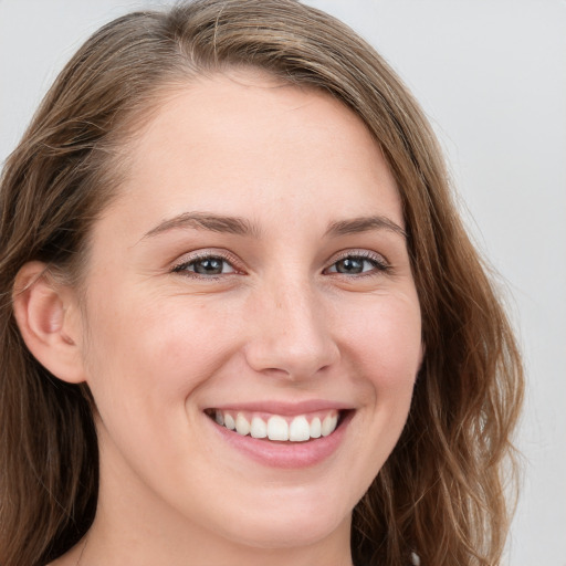 Joyful white young-adult female with long  brown hair and blue eyes