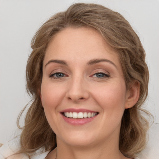 Joyful white young-adult female with long  brown hair and blue eyes