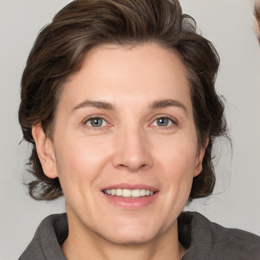 Joyful white adult female with medium  brown hair and grey eyes