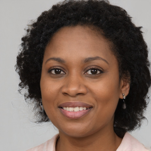 Joyful black young-adult female with long  black hair and brown eyes