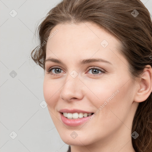 Joyful white young-adult female with long  brown hair and grey eyes