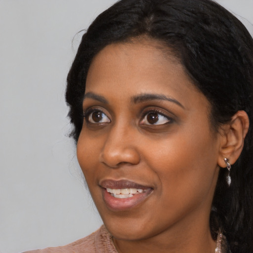 Joyful black young-adult female with long  black hair and brown eyes