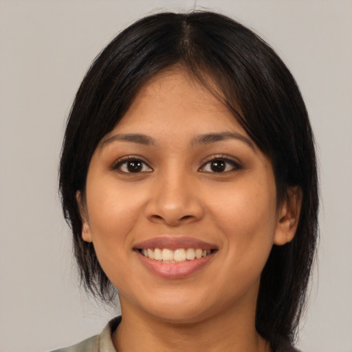 Joyful latino young-adult female with medium  brown hair and brown eyes