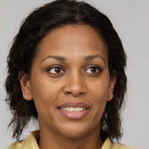Joyful black young-adult female with long  brown hair and brown eyes