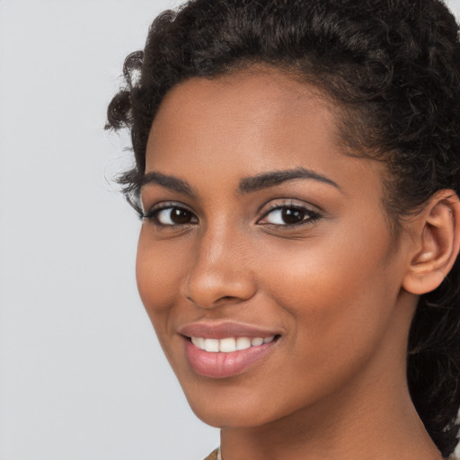 Joyful black young-adult female with long  brown hair and brown eyes