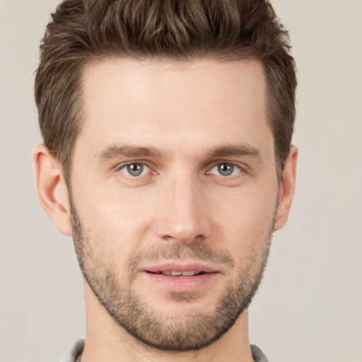 Joyful white young-adult male with short  brown hair and grey eyes