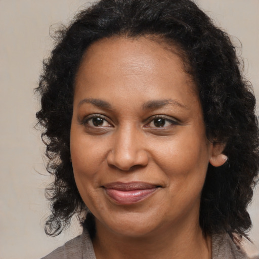 Joyful black adult female with long  brown hair and brown eyes