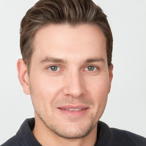 Joyful white young-adult male with short  brown hair and grey eyes