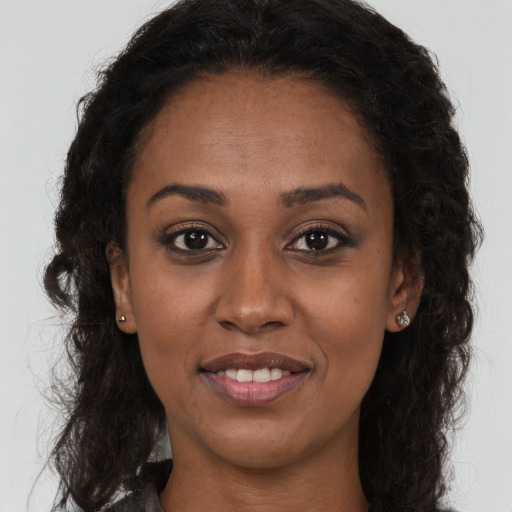 Joyful black young-adult female with long  brown hair and brown eyes