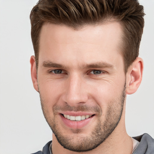 Joyful white young-adult male with short  brown hair and grey eyes