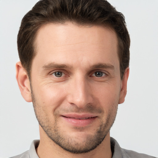 Joyful white young-adult male with short  brown hair and grey eyes