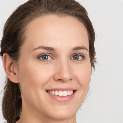 Joyful white young-adult female with medium  brown hair and grey eyes