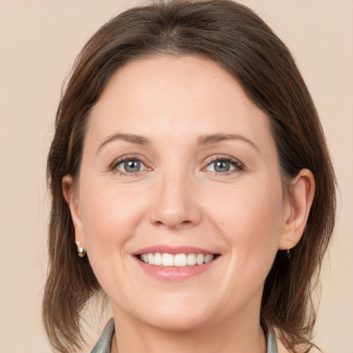 Joyful white young-adult female with medium  brown hair and grey eyes