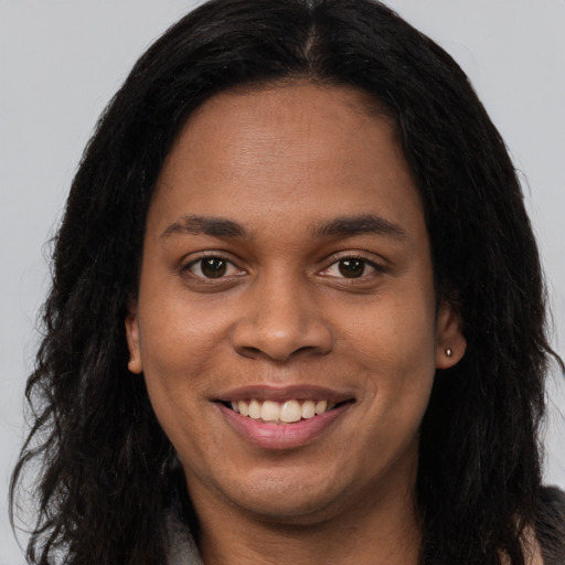 Joyful black young-adult female with long  brown hair and brown eyes