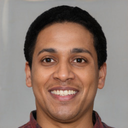 Joyful latino young-adult male with short  black hair and brown eyes