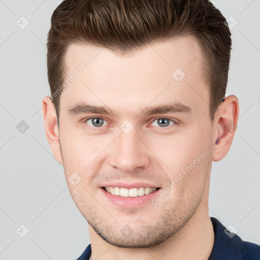 Joyful white young-adult male with short  brown hair and grey eyes