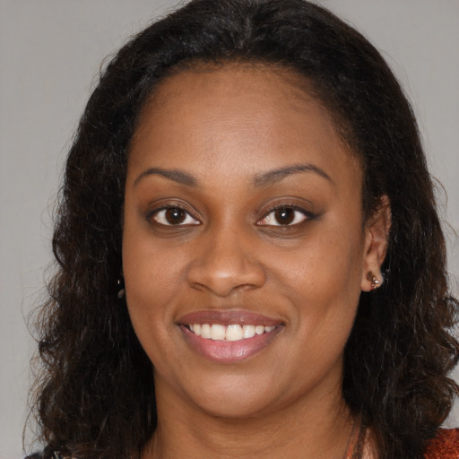 Joyful black young-adult female with long  brown hair and brown eyes