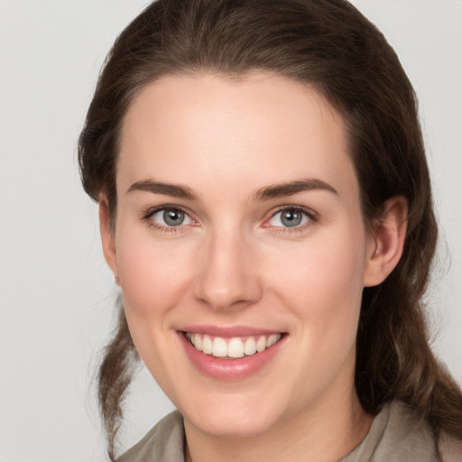 Joyful white young-adult female with medium  brown hair and grey eyes