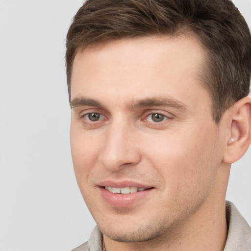 Joyful white young-adult male with short  brown hair and grey eyes