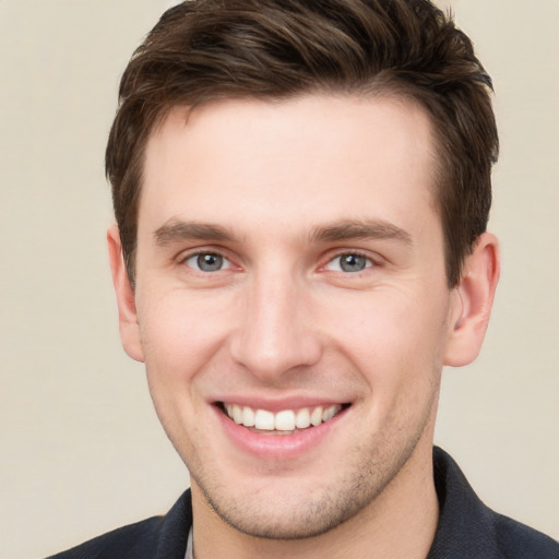 Joyful white young-adult male with short  brown hair and grey eyes